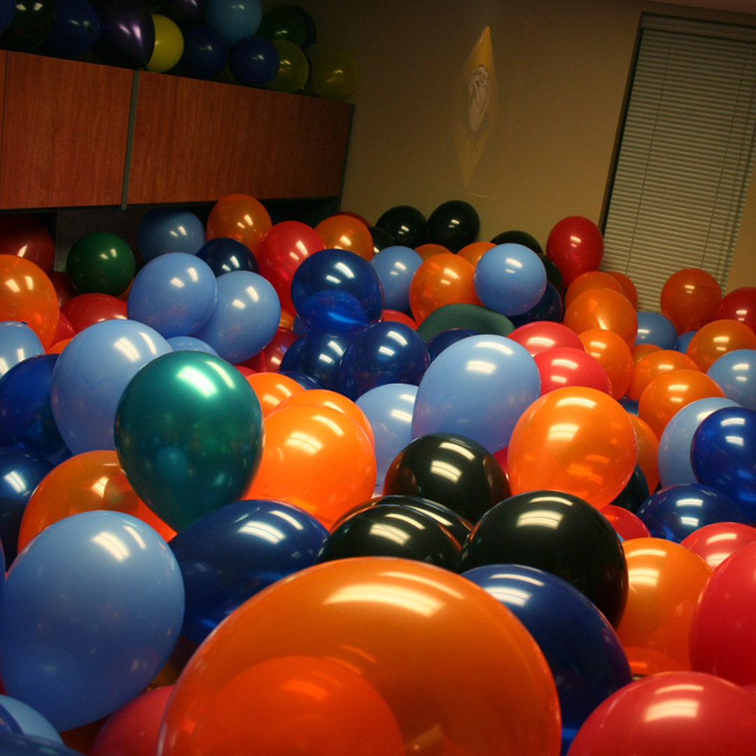 an office full of light blue, dark blue and orange balloons