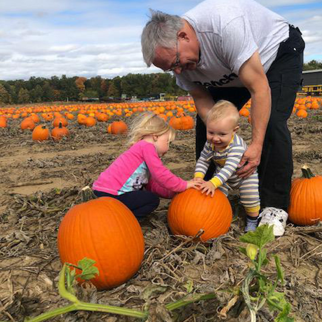 Man, baby boy and young girl touching a pumpkin