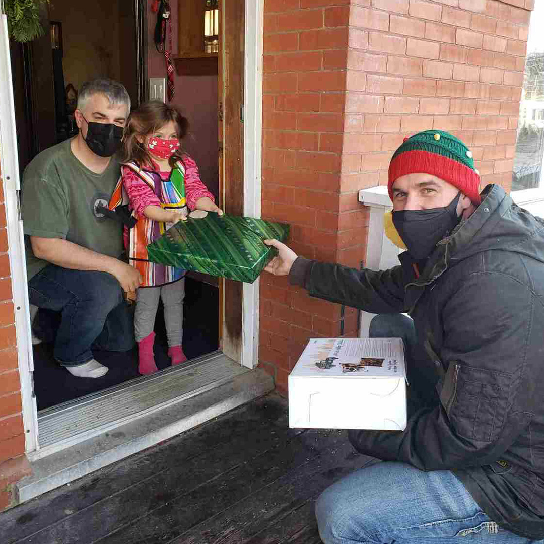 man giving little girl a present at the front door of a house