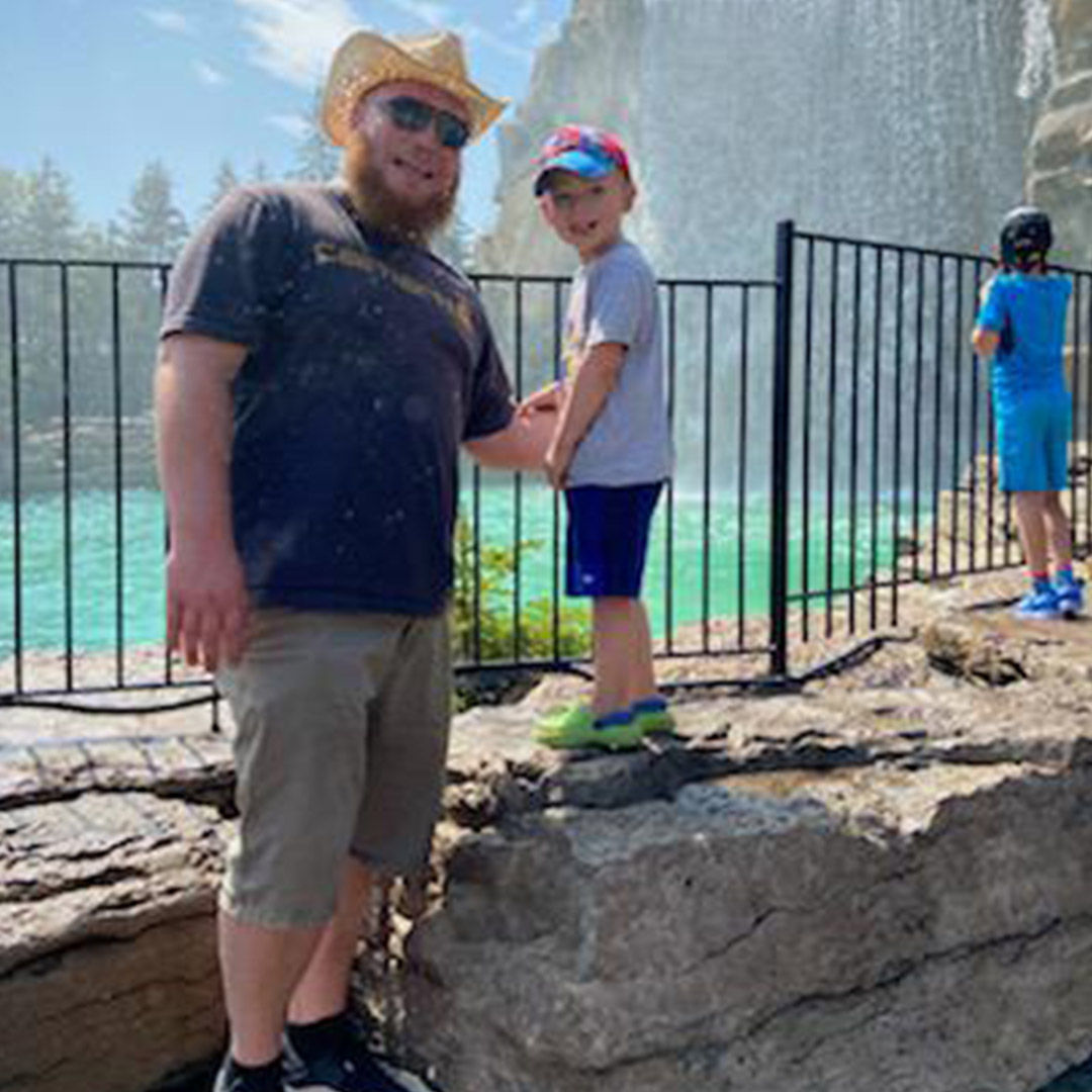 Dad and small boy standing infront of a pool of water