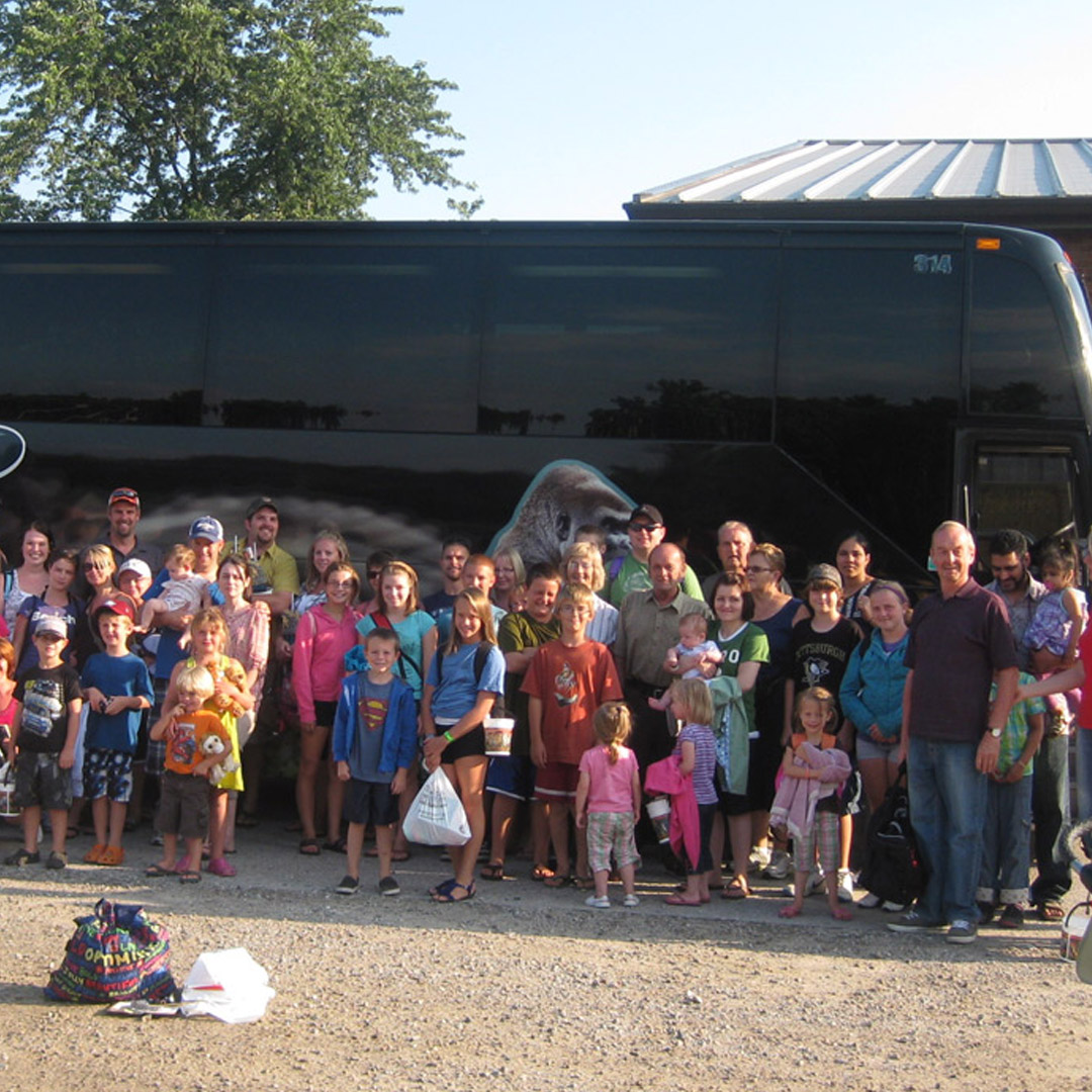 large group of families standing outside a large bus